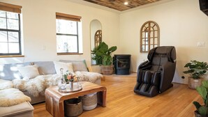 A cozy living room with a sofa, a massage chair, a fireplace, and a large mirror.