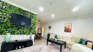 Ein Wohnzimmer mit grüner Wand, einer Couch, einem Couchtisch und einem Fernseher.