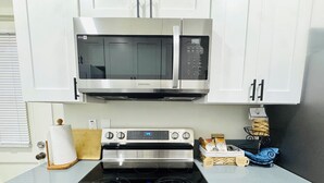Eine Küche mit Mikrowelle, Backofen und Herd aus Edelstahl.