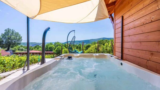 A hot tub with a wooden cabin backdrop and a clear view of the surrounding landscape. - Holiday home with hot tub and sun terrace (Grižane)