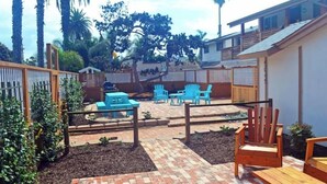 A backyard with a patio area, outdoor seating, and a wooden fence.