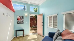 A room with a blue wall, a door leading outside, a small table, and a blue couch with a pillow.