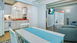 A compact living space with a kitchenette, a dining area, and a bedroom.