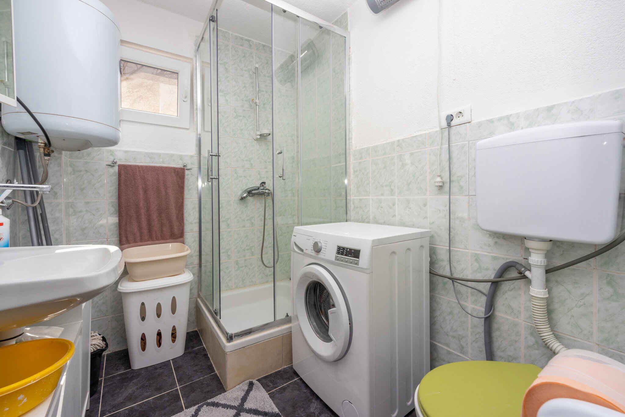 Un bagno compatto con doccia, WC e lavatrice.