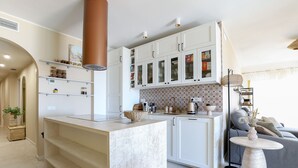 Una cocina moderna con armarios blancos, una isla central y una zona de comedor con una mesa redonda.