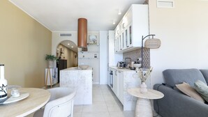 Una cocina moderna con armarios blancos, una isla central y un sofá gris.