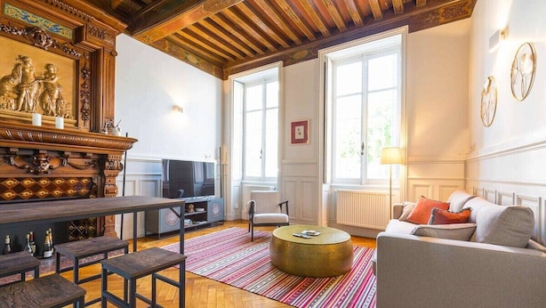 Una sala de estar con techo de madera, un sofá, una mesa de centro, un televisor y una chimenea con un fuste decorativo.