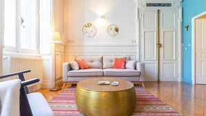 Una sala de estar con un sofá, una mesa de centro redonda y una alfombra estampada.