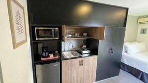 Uma cozinha compacta equipada com micro-ondas, cafeteira e pia.