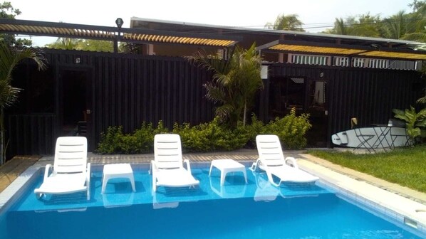 Ein Pool mit weißen Liegestühlen und einem überdachten Bereich.