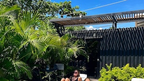 Piscina com duas espreguiçadeiras e uma pérgula.