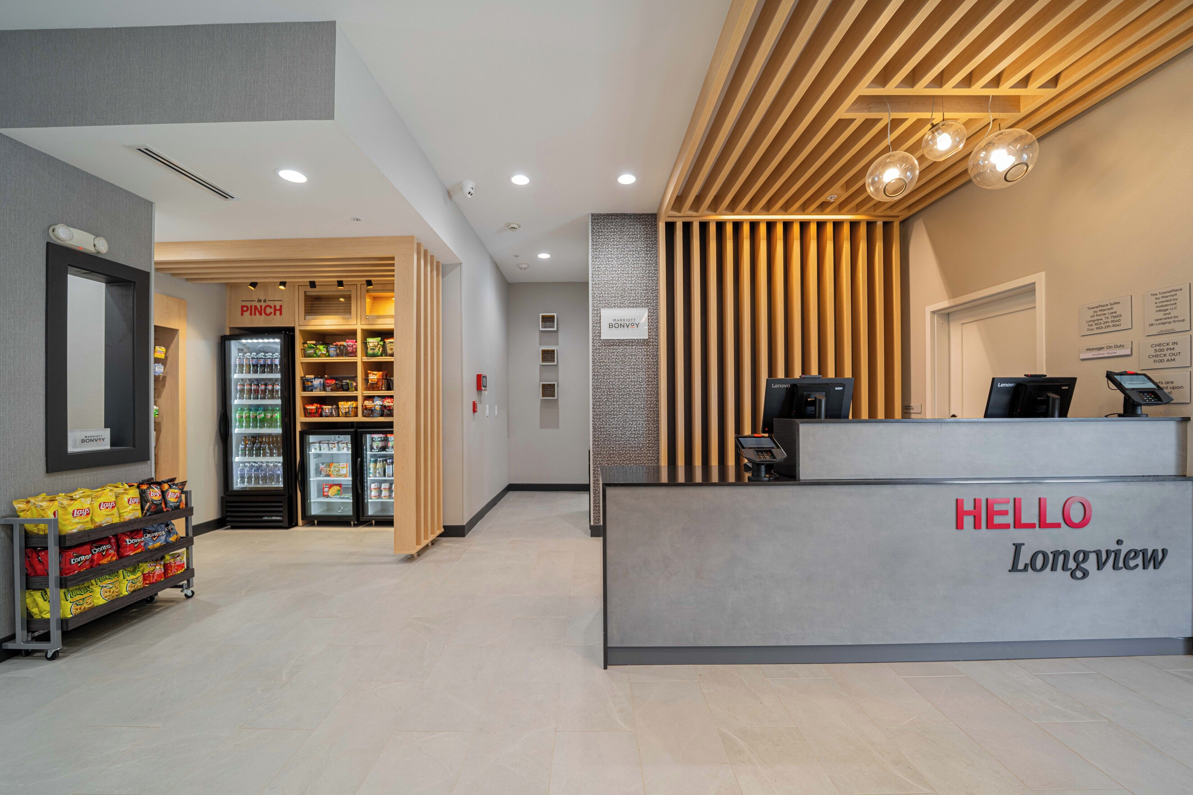 A reception area with a 'HELLO Longview' sign, a snack bar with a 'PINCH' sign, and a refrigerator stocked with beverages.