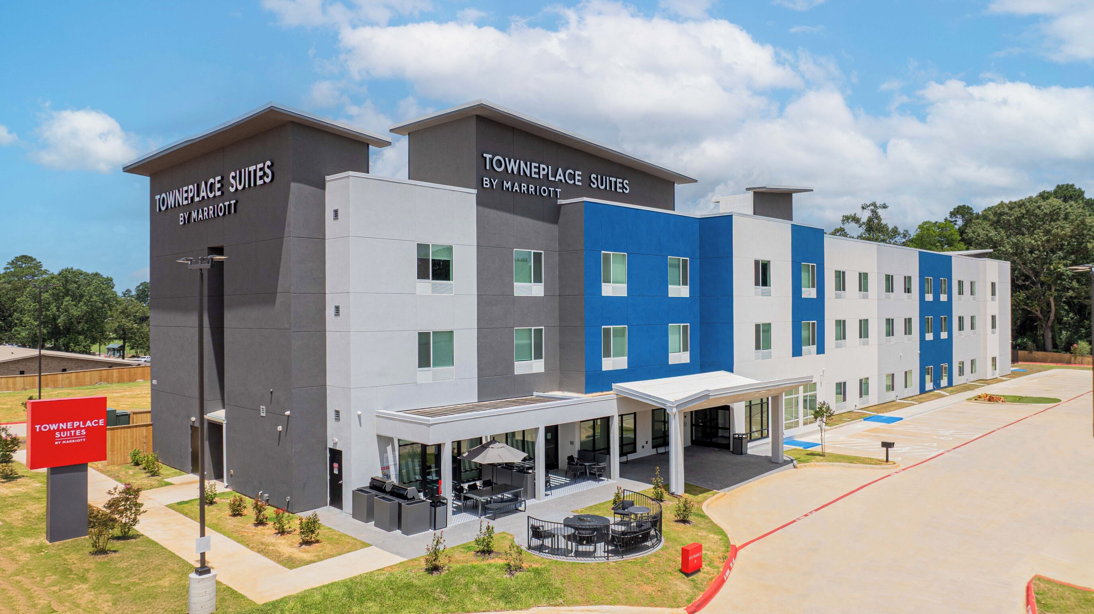 A modern hotel with two-story buildings, outdoor seating, and a covered entrance.