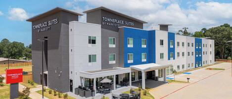 A modern hotel with two-story buildings, outdoor seating, and a covered entrance.