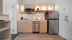 Una cucina compatta con frigorifero in acciaio inossidabile, microonde e lavastoviglie.