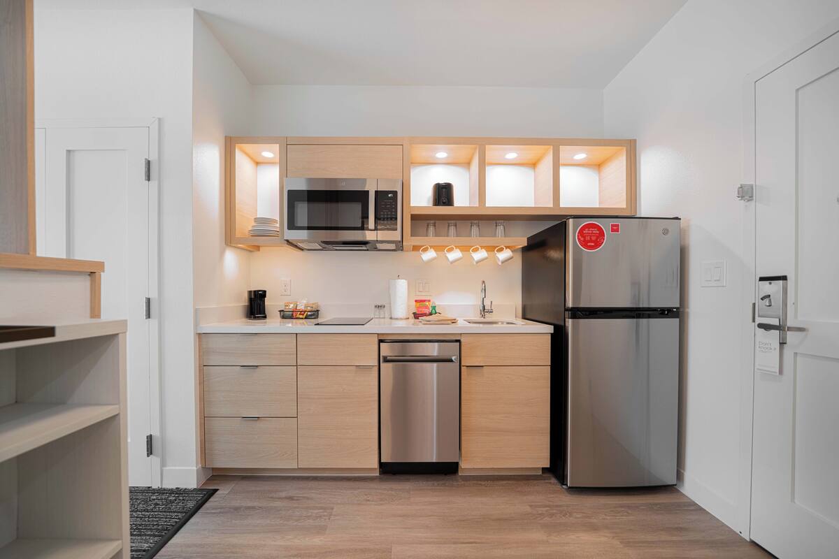 A compact kitchen with a stainless steel refrigerator, microwave, and dishwasher.