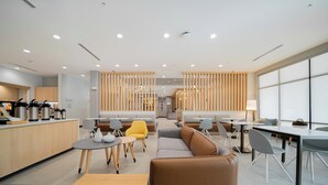 Un'area lounge moderna con posti a sedere, tavoli e una cucina accessoriata.