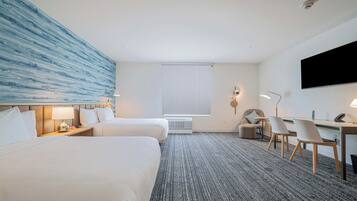 Een hotelkamer met twee bedden, een bureau, een stoel, een televisie en een groot blauw kunstwerk aan de muur.