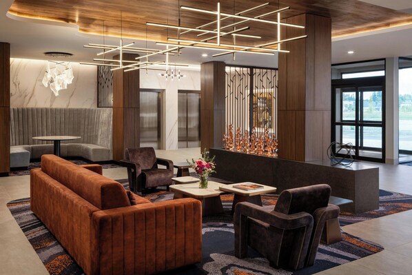 A modern lobby with a sofa, chairs, a coffee table, and a decorative wall.