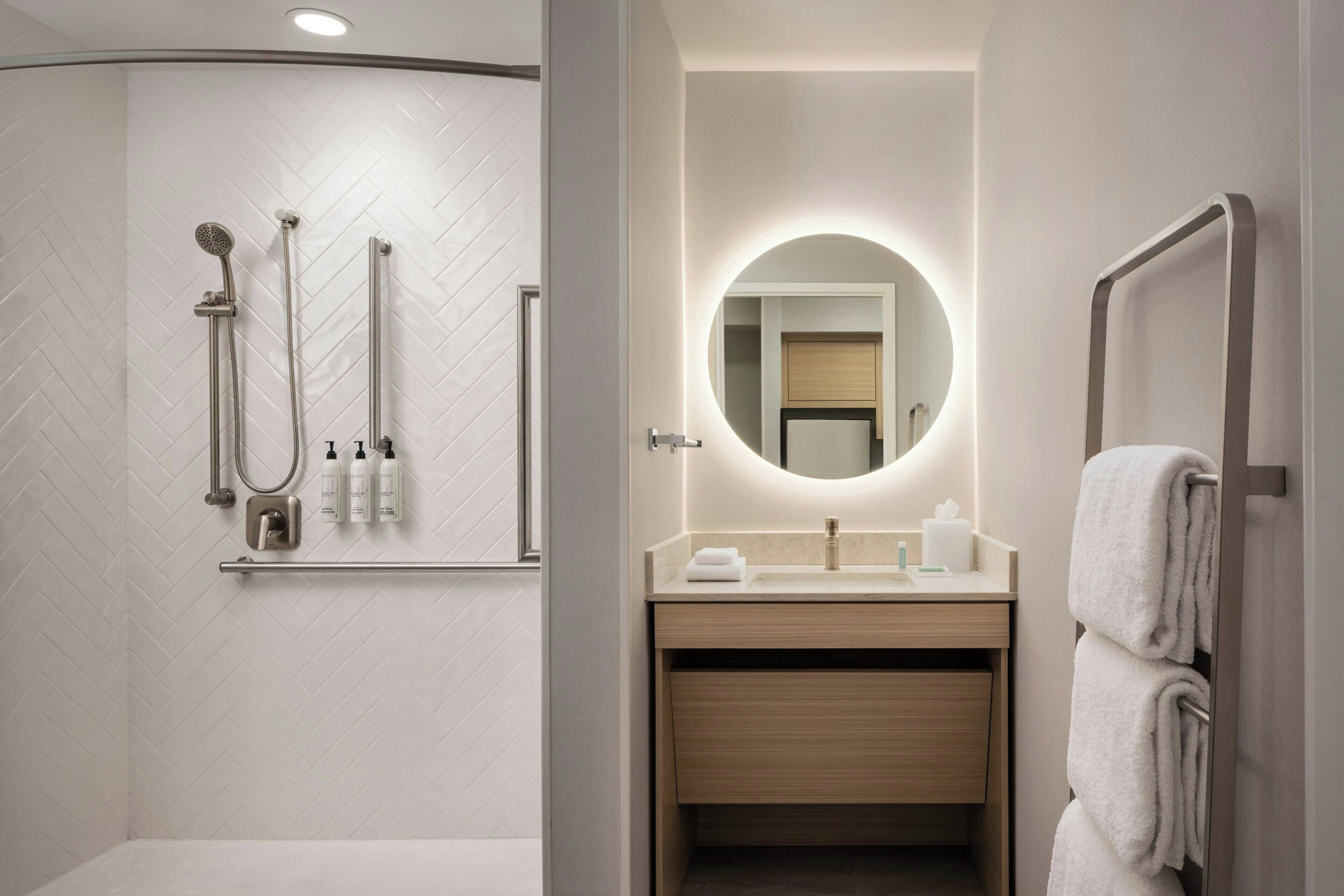 Un baño moderno con ducha, lavamanos con espejo y barra para toallas.