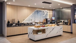 Una cocina moderna con una isla de mármol, armarios de madera y diversos electrodomésticos.