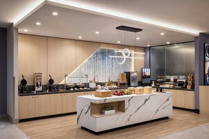 A modern kitchen with a marble island, wooden cabinets, and a variety of appliances.