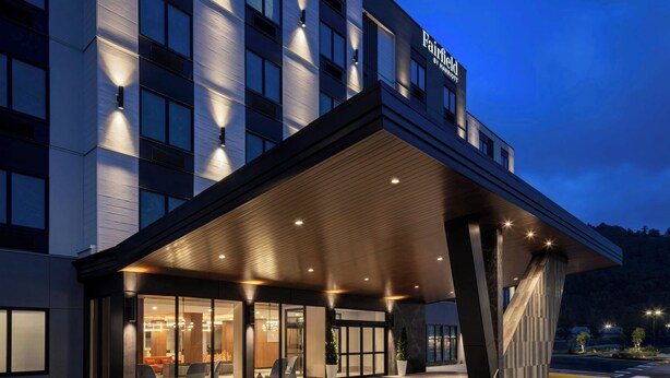 Un hotel moderno con entrada cubierta, ventanas amplias y un cartel que dice "Fairfield by Marriott."