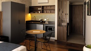Una cocina compacta con microondas, un lavabo y una pequeña zona de comedor con mesa y sillas.