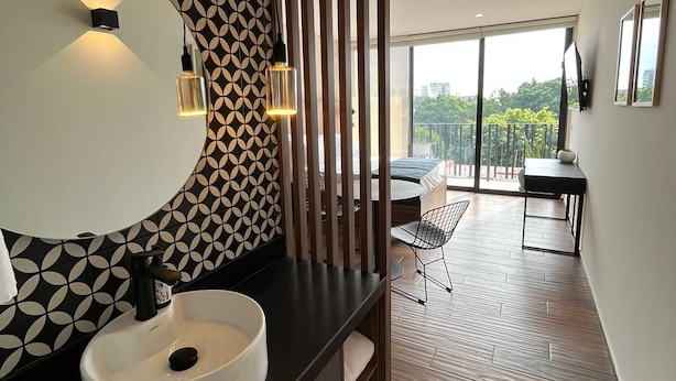 A modern bathroom with a large white sink, black countertop, and patterned wall. - Lapso at Asís (Guadalajara)