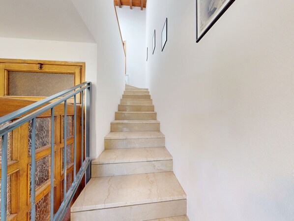 Una escalera con escalones de mármol, una puerta de madera y una barandilla de metal.