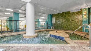 An indoor pool area with a hot tub, a tiled floor, and a green textured wall.
