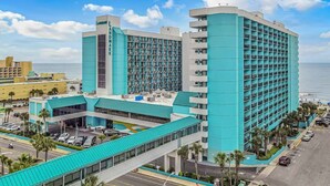 A multi-story hotel with a prominent 'Landmark' sign, a parking area, and a view of the ocean.