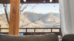 A view from inside a cabin with a wooden railing, looking out to a mountainous landscape. - 5BR, Heated Pool/Spa + Mtn View, Games, Karaoke, Firepit, 15 Min to PF (Sevierville)