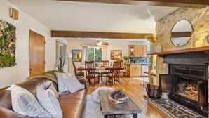 A living room with a fireplace, a dining area, and a kitchen.
