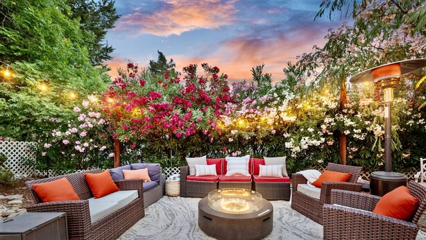 An outdoor seating area with wicker furniture and a central fire feature.
