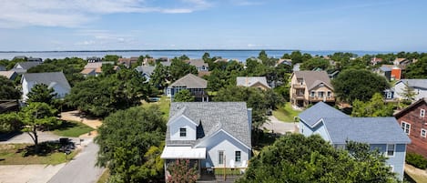 A residential area with houses, a clear sky, and a body of water in the background.