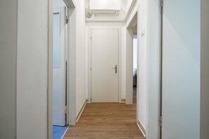 Ein schmaler Korridor mit Holzboden, der zu einer geschlossenen Tür führt.