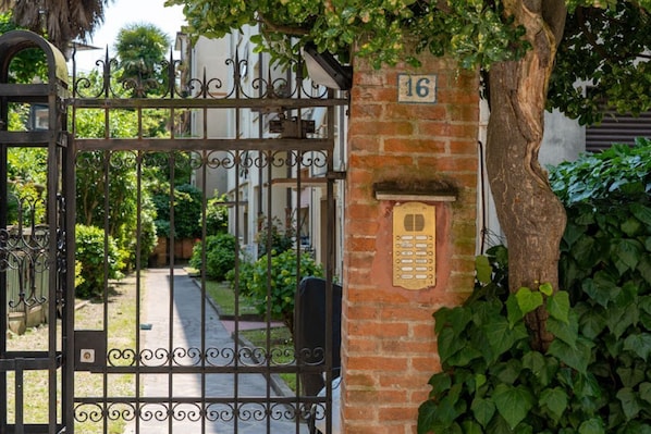Una entrada protegida por un muro de ladrillo y una placa con un número.