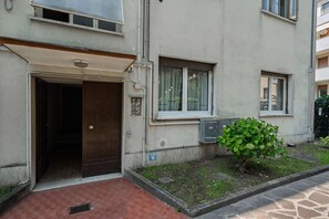 A building with a door, windows, and a small green bush.