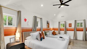 Una camera d'albergo con due letti, una ventola a soffitto e una finestra con tende.