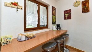 Eine Küche mit einer Holzauskładung, zwei Barhocker, einer Kaffeemaschine und Dekoration an der Wand.
