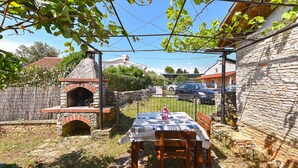 Un espace de restauration extérieur rustique, avec un four en briques, une table avec un set de table et une chaise.