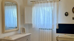 Une salle de bain avec un miroir, un tableau encadré, un radiateur et un téléviseur.