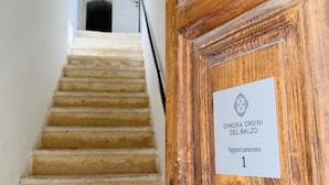 Une porte en bois portant une plaque indiquant : « Dimora Orsini Del Balzo, appartement 1 ».