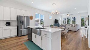 A modern kitchen with white cabinetry, stainless steel appliances, and a central island. - Tranquil Tides Orange Beach Getaway (Orange Beach)