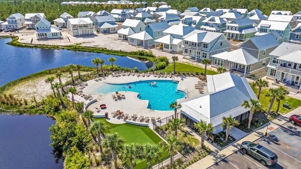 A resort with multiple buildings, a central swimming pool, and a body of water. - Tranquil Tides Orange Beach Getaway (Orange Beach)