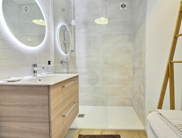 A modern bathroom with a wooden vanity, a glass shower enclosure, and a white bathtub. - ClémentIne - ELVEN - Gîte (ELVEN)