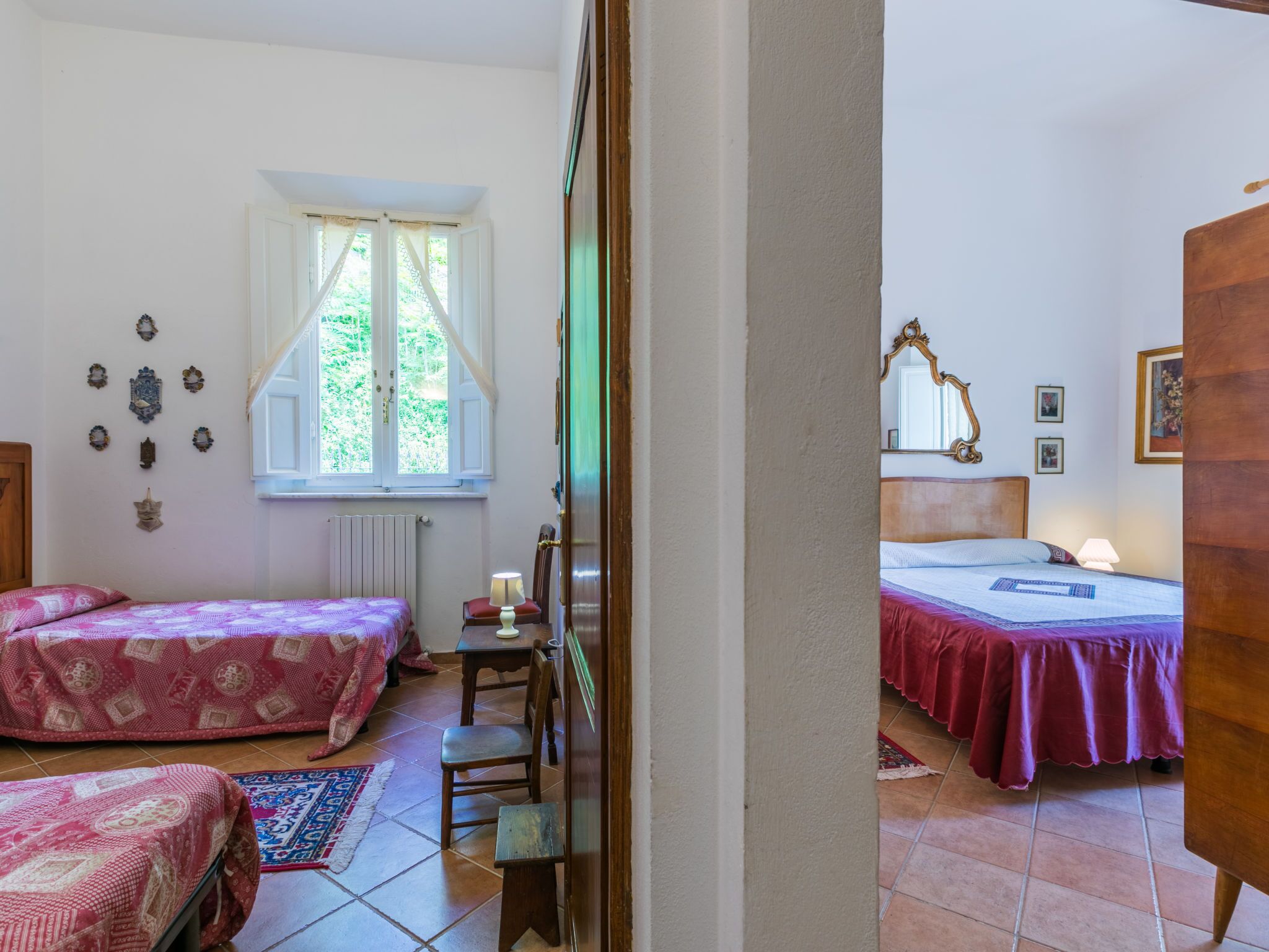 Una camera da letto con due letti, una finestra, un termosifone, un tavolino e una sedia.