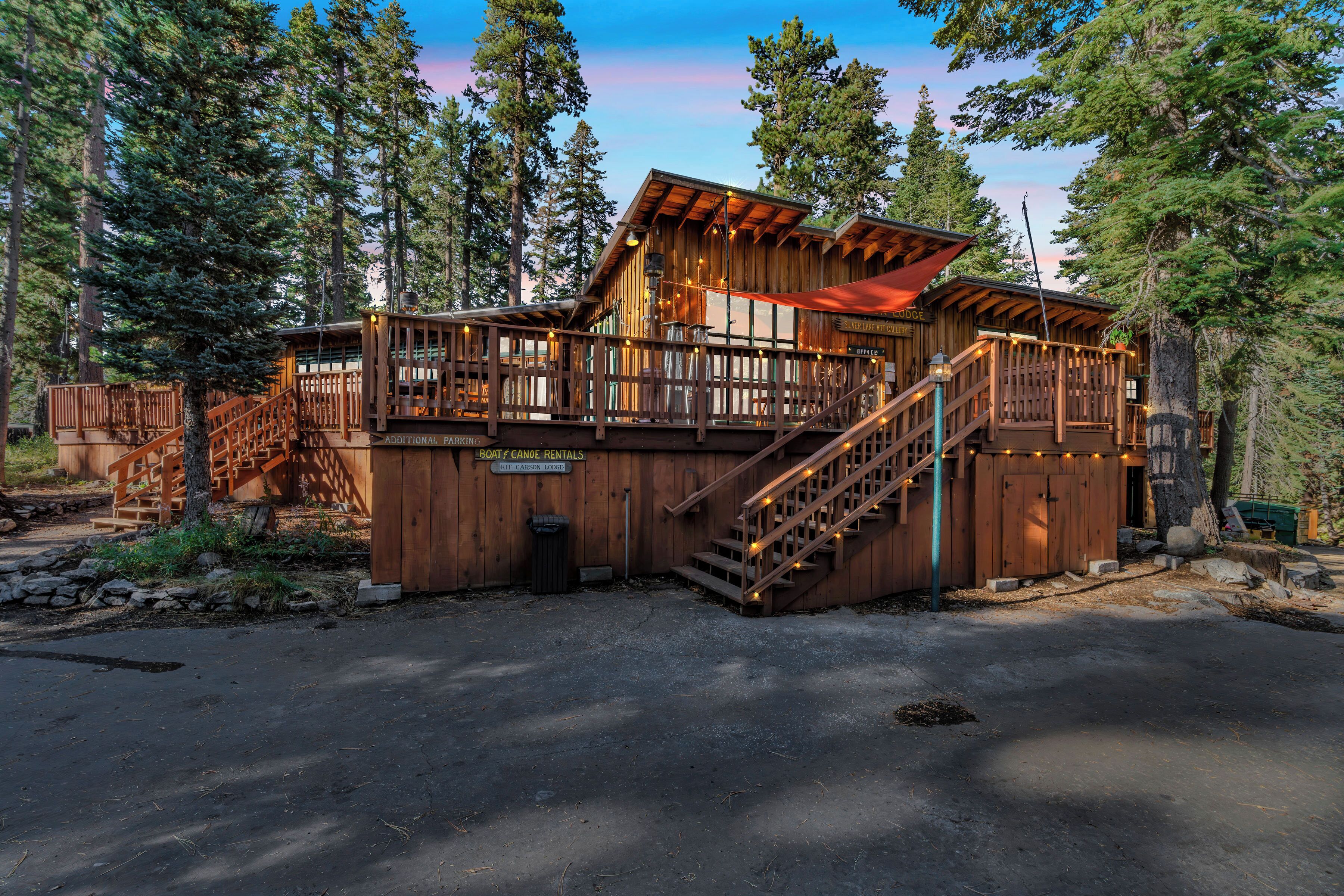 A wooden cabin with a deck and stairs, surrounded by trees.