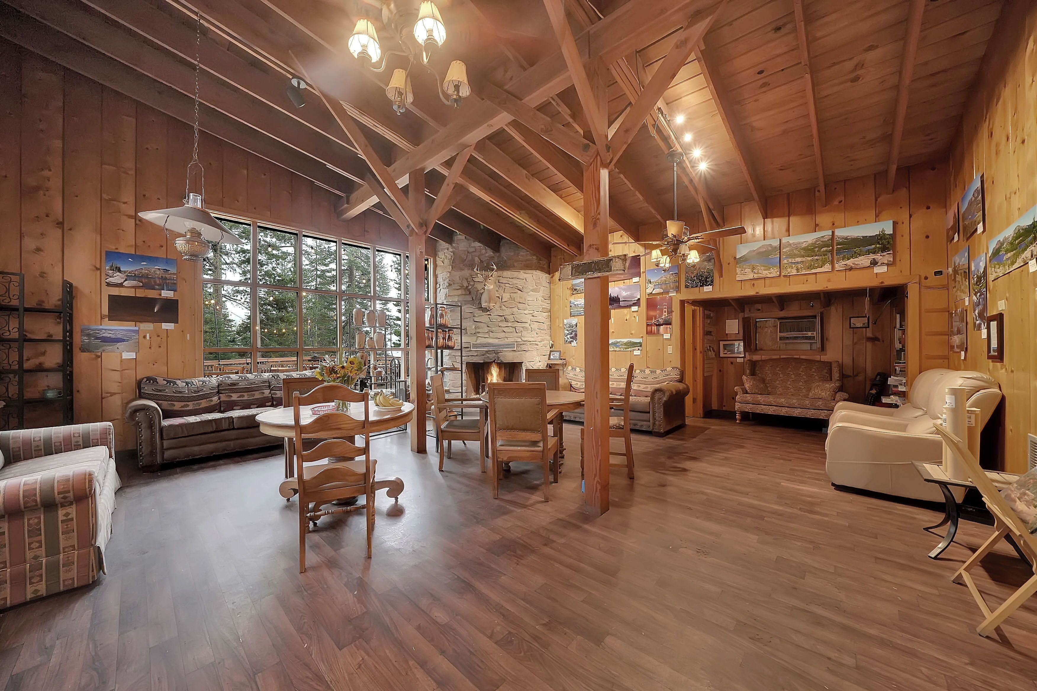 Interior acogedor de una cabaña de madera con comedor, sofás y chimenea.